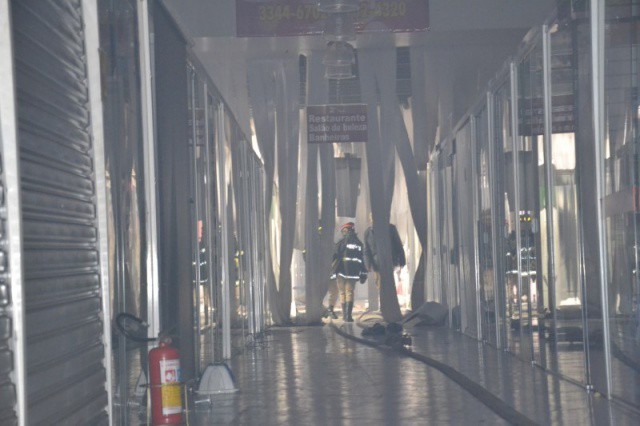 Bombeiros na parte dos fundos do centro comercial ao lado da loja destruída. (Foto: Simão Nogueira)