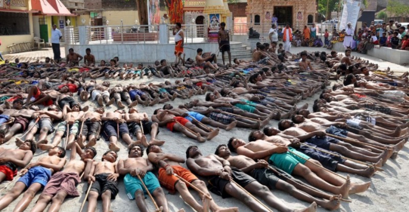 Agricultores indianos deitam no chão com varetas nas mãos para orar por chuva em um templo da periferia de Ranchi, na Índia, durante o Festival Manda (AFP/UOL)