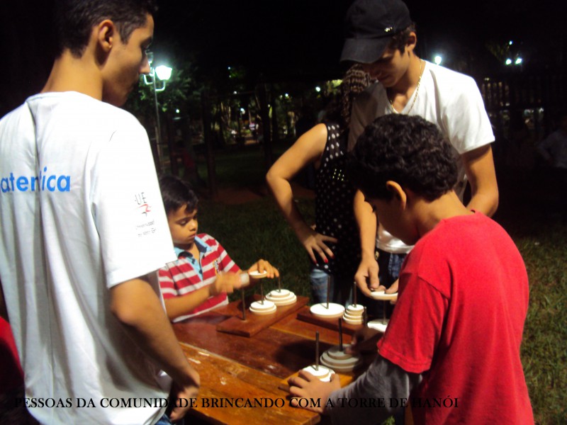 Pessoas da comunidade brincando com a torre de hanói