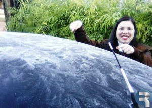 Professora mostra neve sobre capô de carro. (Foto: A Gazeta News)