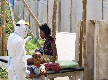 Um agente de saúde do Médicos Sem Fronteiras alimenta uma vítima do ebola em um centro de tratamento de Serra Leoa (Foto: Dunlop/UNICEF / Reuters)