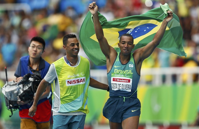 Ricardo Costa comemora ouro ao lado de guia com a bandeira do Brasil nas mãos (Foto: Reuters)