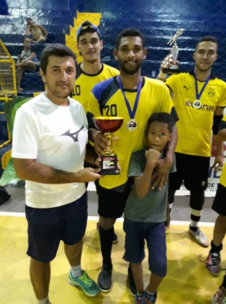 O diretor de esportes Clóves Lima entrega taça ao time Reparos, campeão do campeonato de férias de futsal em Cassilândia.