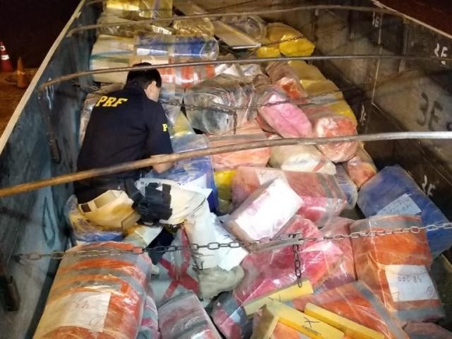 Policial fiscaliza fardos de maconha encontrados em carreta. (Foto: Adilson Domingos)
