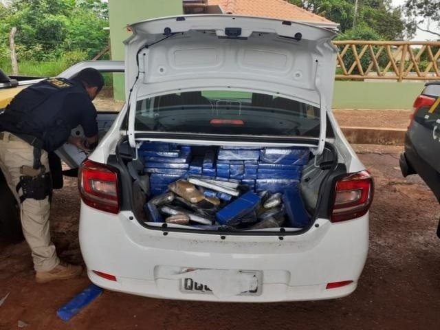Policial retirando os tabletes da droga do veículo. (Foto: Divulgação/PRF)