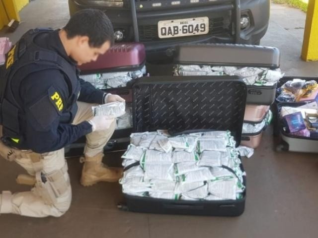 Policial vistoriando os produtos encontrados nas malas. (Foto: Divulgação)