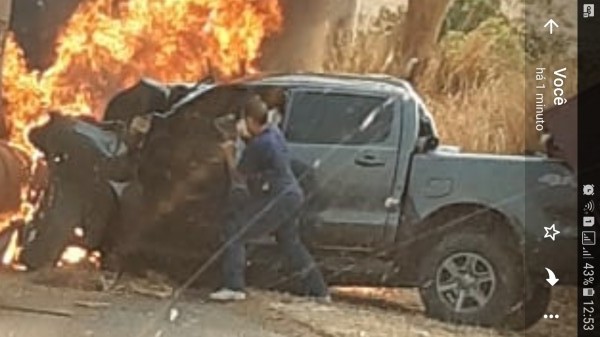 A foto no momento em que Flávio lutava para retirar a vítima de dentro da caminhonete pegando fogo . 